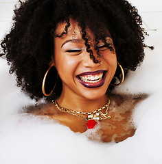 Image showing young afro-american teen girl laying in bath with foam, wearing 