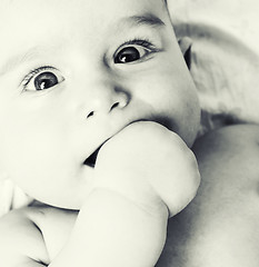 Image showing little sweet baby close up, hand in mouth smart looking