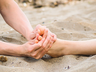 Image showing Foot massage on a beach in sand, male and female caucasian