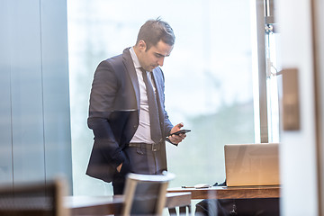 Image showing Businessman looking at smart phone in modern corporate office.