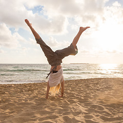 Image showing Free Happy Woman Turning Cartwheel Enjoying Sunset on Sandy Beach.