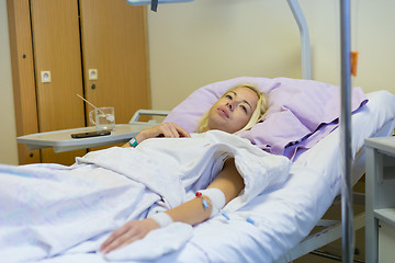 Image showing Bedridden female patient recovering after surgery in hospital care.