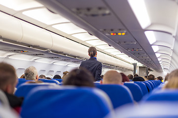 Image showing Stewardess walking the aisle of commercial airplane.