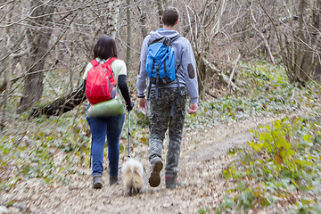 Image showing Young couple with a dog walking in the woods, blurred motion