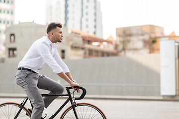 Image showing man with headphones riding bicycle on city street