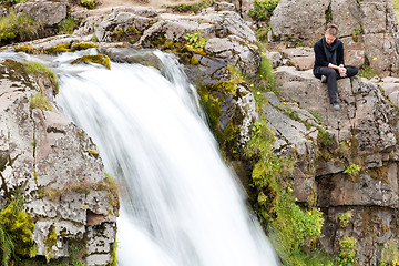 Image showing Woman at Kirkjufellsfoss waterfall near the Kirkjufell mountain