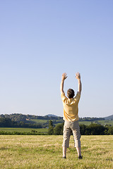 Image showing Man with uplifted arms in a meadow