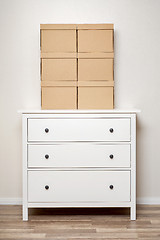 Image showing Cardboard boxes on white wooden commode