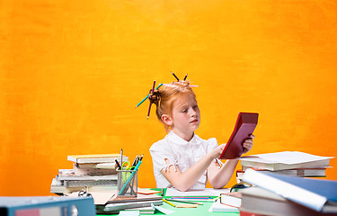 Image showing The Redhead teen girl with lot of books at home. Studio shot