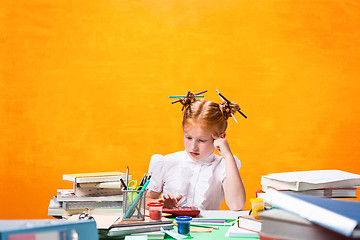 Image showing The Redhead teen girl with lot of books at home. Studio shot