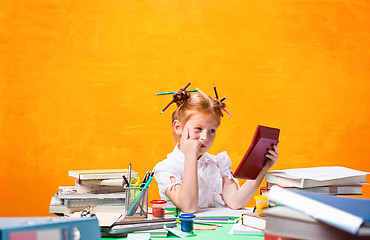 Image showing The Redhead teen girl with lot of books at home. Studio shot