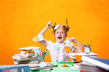 Image showing The Redhead teen girl with lot of books at home. Studio shot