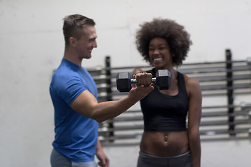 Image showing black woman doing bicep curls with fitness trainer