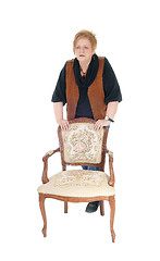 Image showing Senior woman standing on armchair.