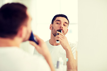 Image showing man shaving mustache with trimmer at bathroom