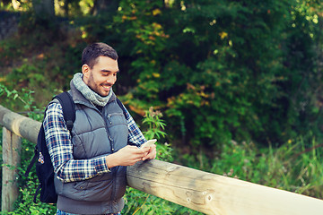 Image showing happy man with backpack and smartphone outdoors