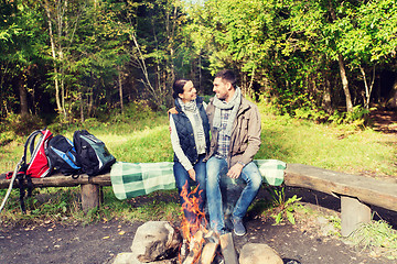 Image showing happy couple sitting on bench near camp fire