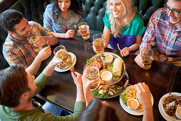 Image showing happy friends eating and drinking at bar or pub