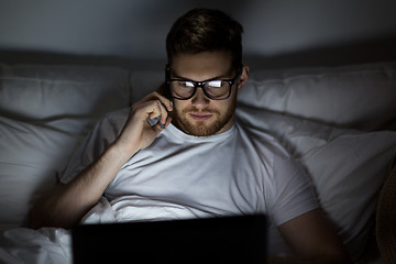 Image showing man with laptop calling on smartphone at night