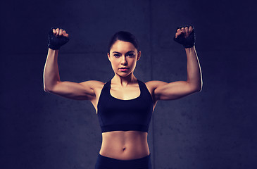 Image showing young woman flexing muscles in gym