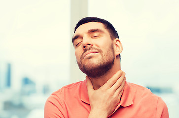 Image showing unhappy man suffering from throat pain at home