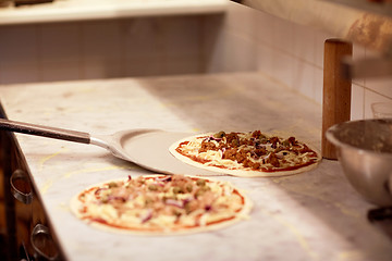 Image showing peel taking pizza off table at pizzeria