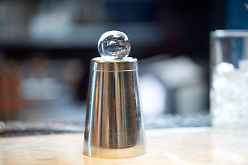 Image showing hand-cut ice ball on top of cocktail shaker at bar