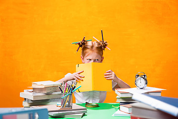 Image showing The Redhead teen girl with lot of books at home. Studio shot