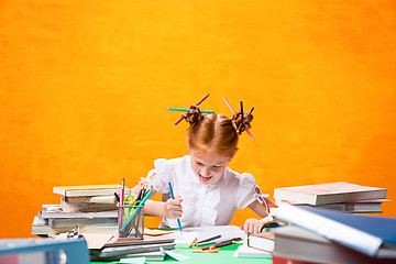 Image showing The Redhead teen girl with lot of books at home. Studio shot