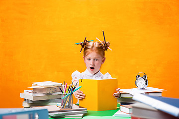 Image showing The Redhead teen girl with lot of books at home. Studio shot