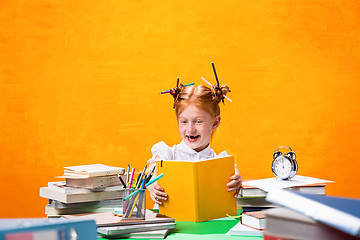 Image showing The Redhead teen girl with lot of books at home. Studio shot