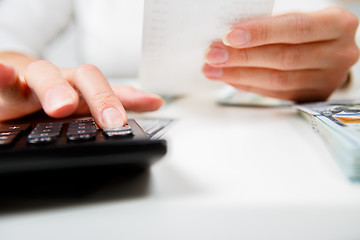 Image showing savings, finances, economy and home concept - close up of hands with calculator counting money and making notes at home