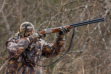 Image showing hunter in camouflage takes aim from a gun