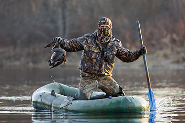 Image showing hunter with a duck in a boat