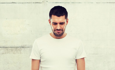 Image showing unhappy young man over gray wall background