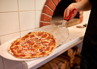 Image showing chef placing pizza from peel to plate at pizzeria