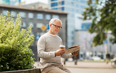 Image showing senior man reading newspaper and drinking coffee