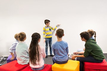 Image showing happy student boy showing something at white wall