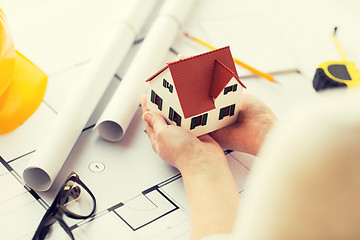 Image showing close up of hands with house model above blueprint