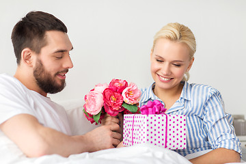 Image showing happy couple with gift box in bed at home