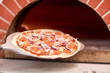 Image showing peel placing pizza into oven at pizzeria