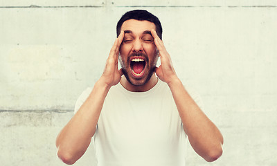 Image showing crazy shouting man in t-shirt over gray wall