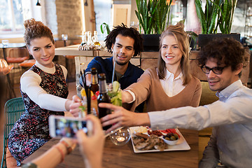 Image showing happy friends clinking drinks at bar or cafe