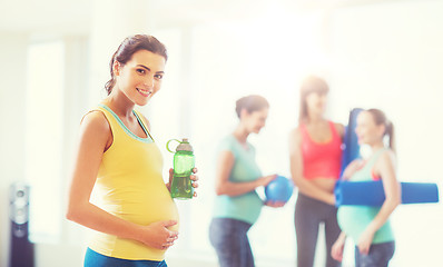 Image showing happy pregnant woman with water bottle in gym