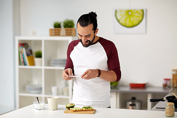 Image showing man photographing food by smartphone at home