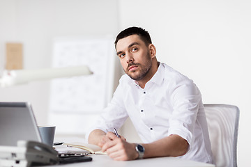 Image showing businessman with laptop and notebook at office