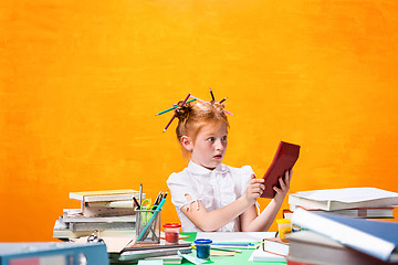 Image showing The Redhead teen girl with lot of books at home. Studio shot