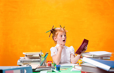 Image showing The Redhead teen girl with lot of books at home. Studio shot