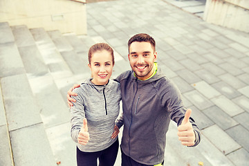 Image showing smiling couple showing thumbs up on city street