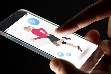 Image showing close up of hands with fitness app on smartphone